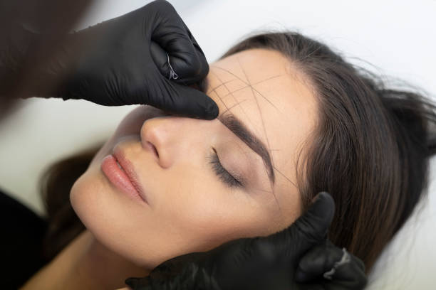 Beautician in the saloon doing the perfect architecture of eyebrows. Beautician is doing a ideal shape of eyebrows with thread. eyebrow stock pictures, royalty-free photos & images