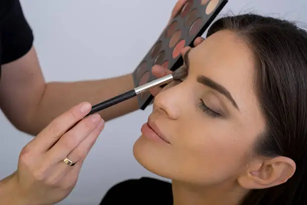 Young woman is doing her make up before night out.