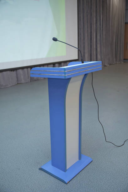 istock Speaker prepare before speaking to the audience behind the podium focused microphone on the podium and blurred empty seat and some of audience . Speech or conference concept. 1131559496