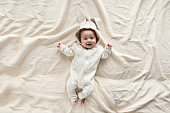 Cute little baby in bunny costume on blanket at home, top view