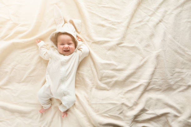 Having fun on Easter day. Baby boy wearing bunny costume with ears smiling.