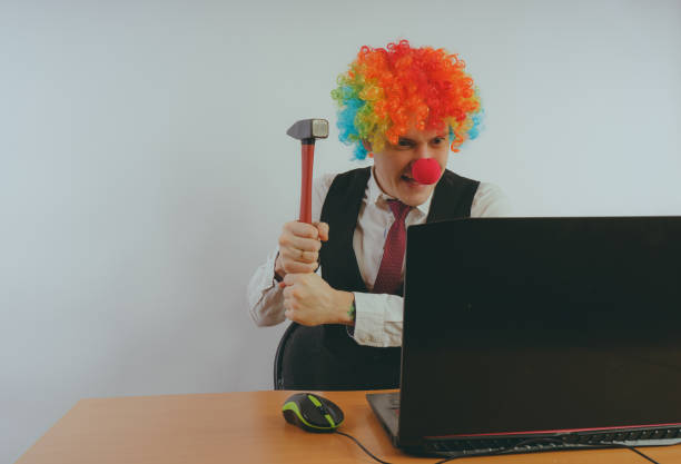 Office worker in clown wig, clown concept at work. Businessman at the computer, work on a laptop face paint halloween adult men stock pictures, royalty-free photos & images
