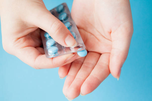 istock Hands opening a package of blue pills against a blue background 1131567285