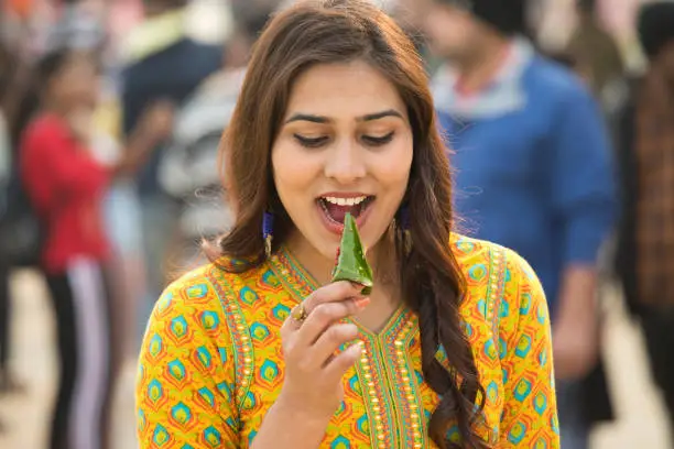 Woman eating sweet ingredients wrapped in betel leaf
