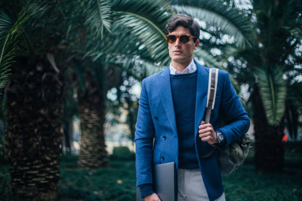istock Businessman with laptop and backpack walking in the park 1131579383