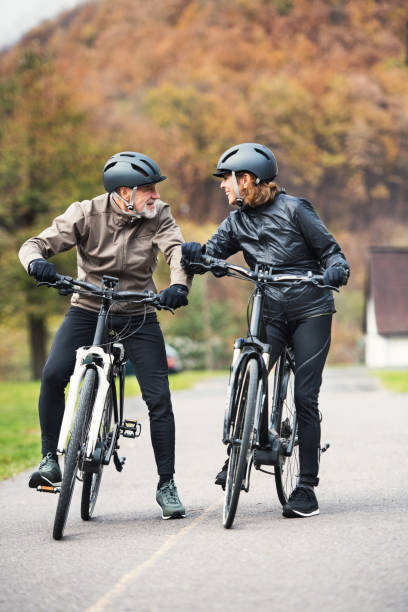 istock Active senior couple with electrobikes standing outdoors on a road in nature. 1131583393