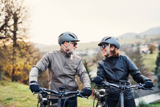 istock Active senior couple with electrobikes standing outdoors on a road in nature. 1131583916