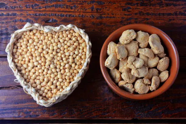 Photo of Soybeans meat, chunks in a brown ceramic bowl. Top view of raw soybeans chunks on rustic wooden background