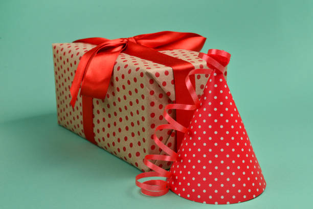 istock Red birthday cap and a present on a green background. Space for text or design. 1131586755