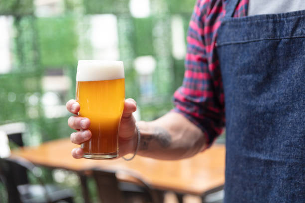 Close up of unrecognizable waiter at a bar holding a beer