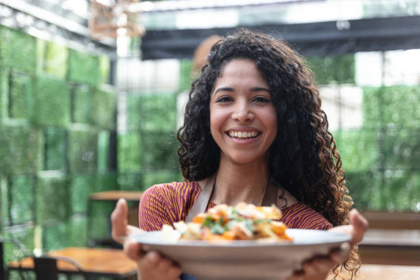 istock Beautiful waitress at a restaurant holding a customer's order while facing camera smiling 1131587095
