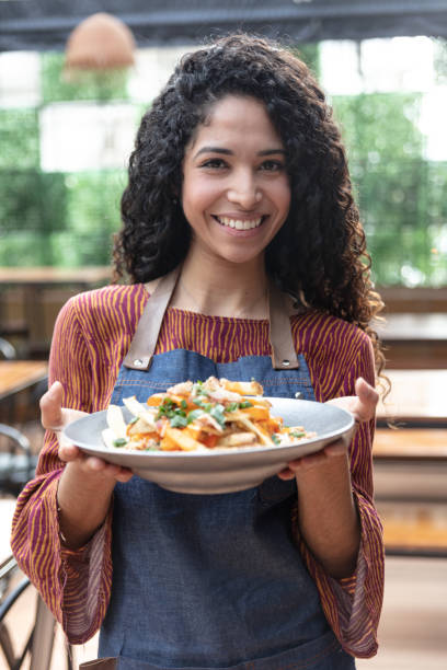 istock Confident beautiful waitress at a restaurant holding an order for customer while facing camera smiling 1131587098
