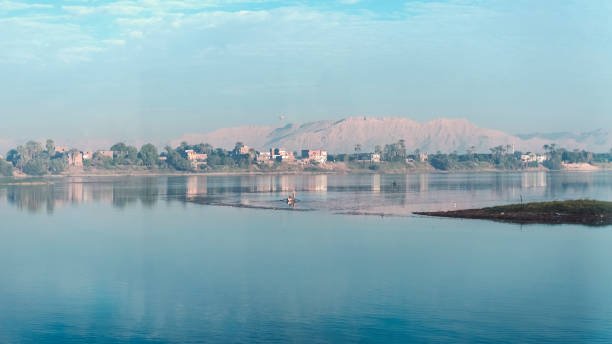 Photo of the nile at dawn with a boat on the still waters.