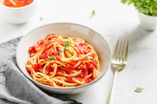 istock Traditional pasta with tomato and Greek basil sauce in a ceramic bowl on a white table. 1131589071