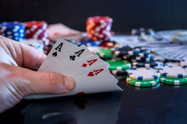 istock Four aces in hand and gambling chips at black 1131589775