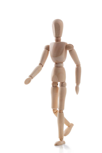 Three quarters front view of a wooden mannequin walking forward isolated on white background. Predominant colors are brown and white. High key DSRL studio photo taken with Canon EOS 5D Mk II and Canon EF 100mm f/2.8L Macro IS USM.