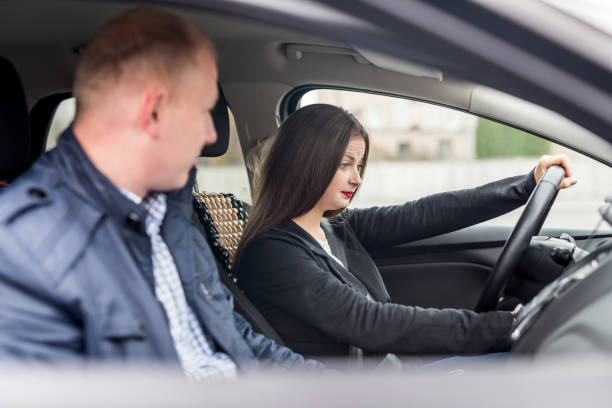 istock Young woman with instructor sitting in car 1131590446