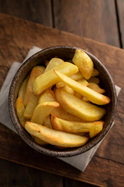 istock Bowl of cooked Oven chips against a dark wood surface. 1131591937