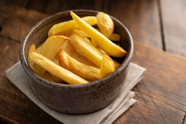 istock Bowl of cooked Oven chips against a dark wood surface. 1131591951