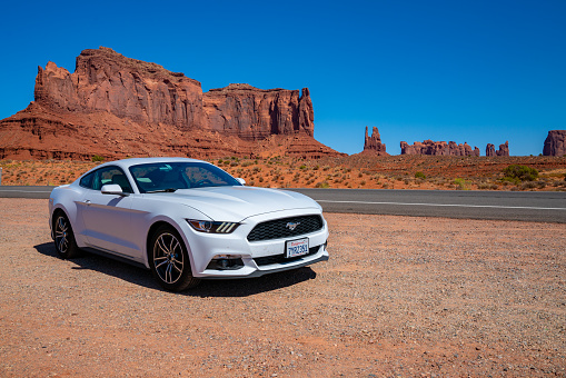 Monument Valley, USA - January 17, 2018: White Ford Mustang GT parked by the side of the road in the heart of the Monument Valley park.