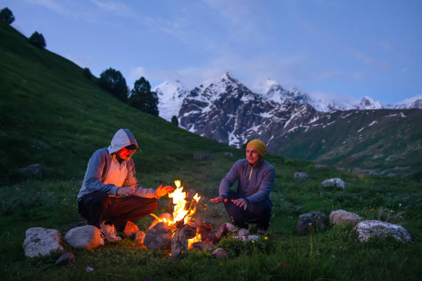 istock Friends sit near fire in camp in mountain 1131593602