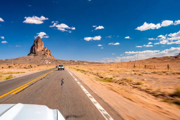 Photo of White Ford Mustang GT driving through Monument Valley