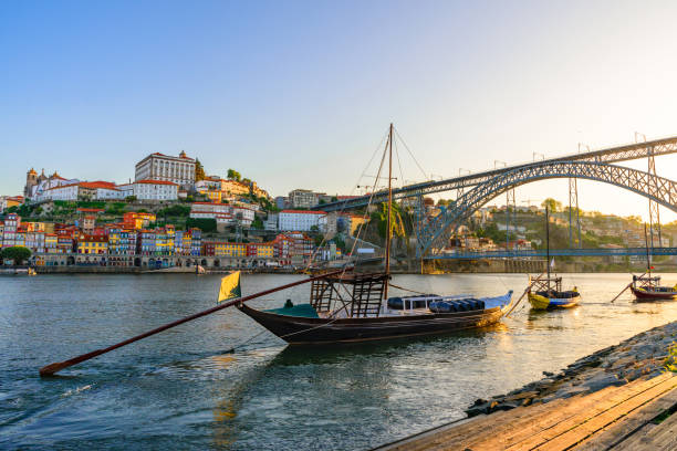 Porto, Portugal old town cityscape on the Douro River with traditional Rabelo boats with wine barrels and bridge Porto, Portugal old town cityscape on the Douro River with traditional Rabelo boats with wine barrels and bridge on the sunrise rabelo boat stock pictures, royalty-free photos & images