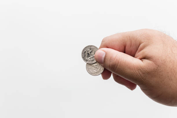 istock Male hand holding two quarter dollar coins, white background 1131600616