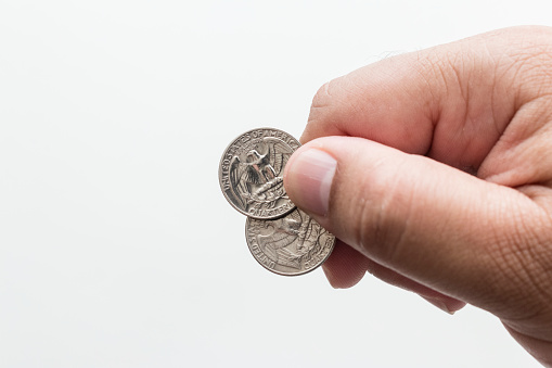 Male hand holding two quarter dollar coins