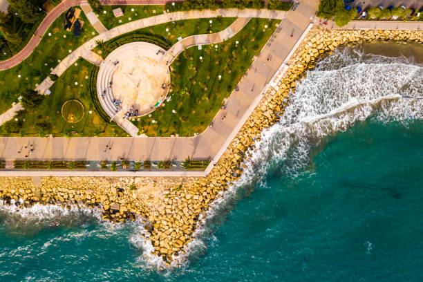 view of Molos Promenade park on coast of Limassol Aerial view of Molos Promenade park on coast of Limassol city centre in Cyprus. Bird's eye view of the jetty, beachfront walk path and palm trees by the sea. limassol marina stock pictures, royalty-free photos & images