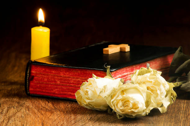istock Old book, withered roses, a yellow candle and a small cross on the book 1131603732