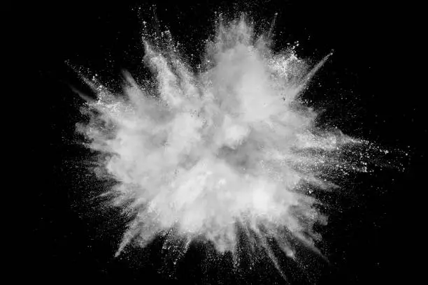Photo of Bizarre forms of white powder explosion cloud against black background.White dust particles splash.