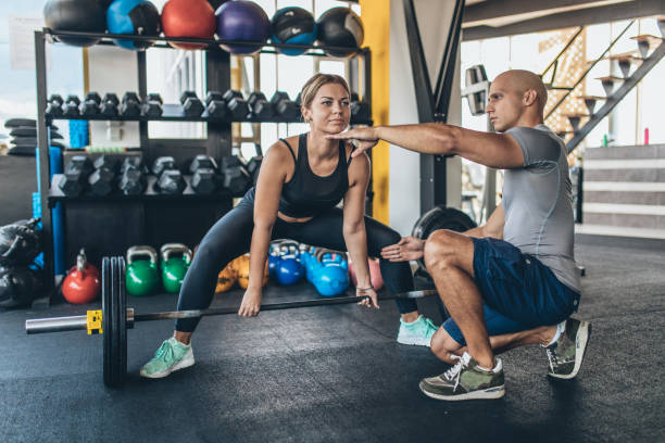 istock Fitness woman exercise with barbell with her personal trainer 1131606849