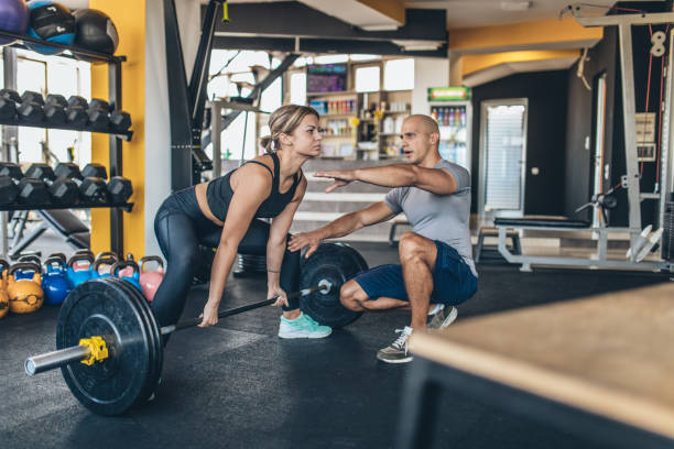 istock Woman exercise with barbell with her personal trainer 1131607362
