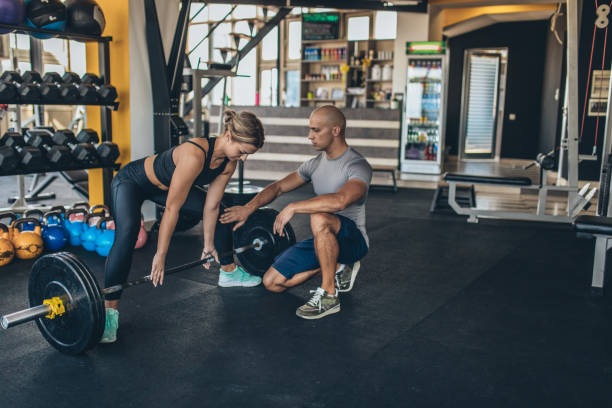 istock Woman exercise with barbell with her trainer 1131608949