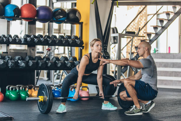 istock Fitness woman exercise with barbell with her personal trainer 1131610228