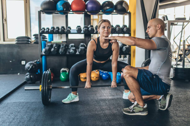 istock Woman exercise with barbell with her personal trainer 1131610348