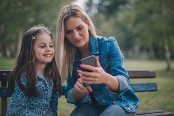 istock Mother and daughther making selfie in park 1131610907