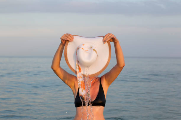 Female figure in sea water with a wide-brimmed hat Female figure in sea water with a wide-brimmed hat obscured face photos stock pictures, royalty-free photos & images