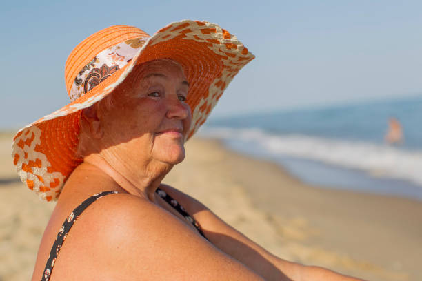Grandmother on vacation. Elderly woman in a bathing suit by the sea. Old man sitting on the beach