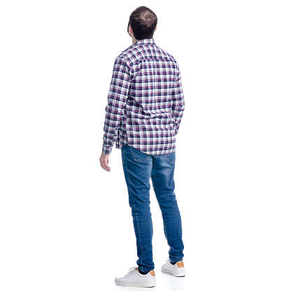 A man in jeans and shirt looks up on a white background. Isolation, back view