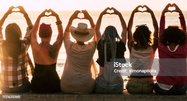 Love And Meditation Lifestyle Concept Group Of Women Looking At The Sunset On The Ocean And Make The Hearth With Hands Romantic Golden Light And Valentines Day Concept Friendship Forever Stock Photo - Download Image Now