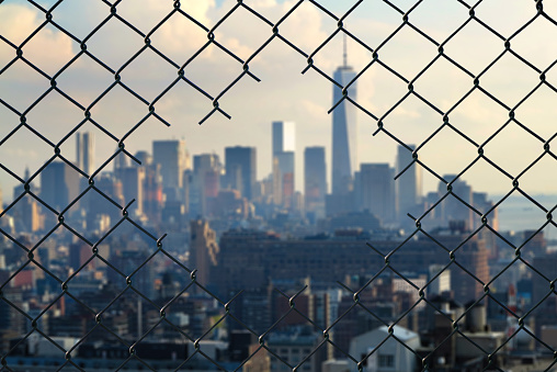 View on the New York city through the hole of steel mesh wire fence. Concept