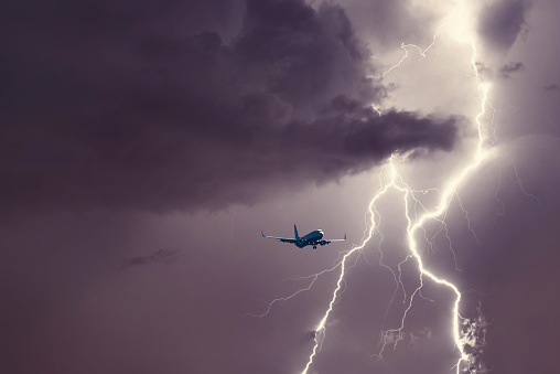 Passenger airplane landing in the stormy weather on the backdrop lightning