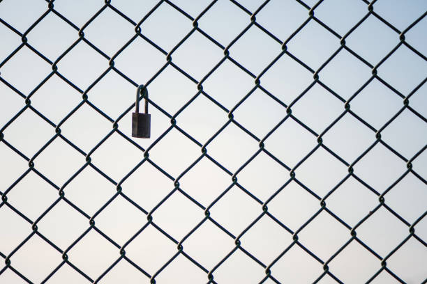 Mesh wire fence with lock on the sky background. Isolated.
