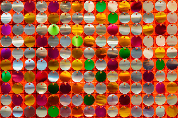 Texture of disk-shaped shiny metals bead sequins and spangles on a colorful decorative background.