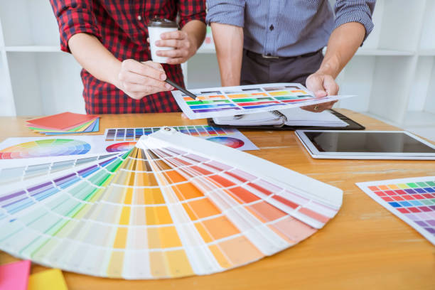 istock Teamwork of young creative designers working on project together and choose color swatch samples for selection coloring on digital graphic tablet at workspace 1131628579