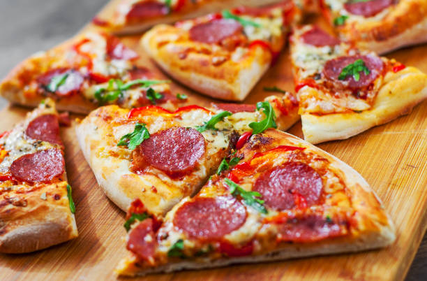 istock Pepperoni Pizza with Mozzarella cheese, salami, Tomatoes, pepper, Spices and Fresh arugula. Italian pizza on wooden table background 1131631074