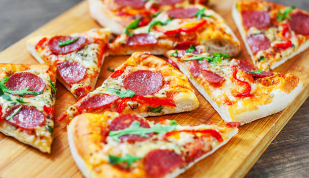 istock Pepperoni Pizza with Mozzarella cheese, salami, Tomatoes, pepper, Spices and Fresh arugula. Italian pizza on wooden table background 1131631079
