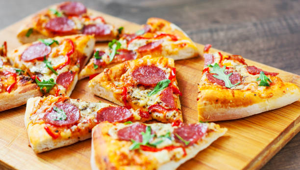 istock Pepperoni Pizza with Mozzarella cheese, salami, Tomatoes, pepper, Spices and Fresh arugula. Italian pizza on wooden table background 1131633712